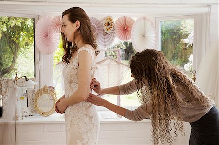 simsearch:6118-08971470,k - A dressmaker taking in a wedding dress, pinning and fitting it to the client, a young woman. A bride selecting her dress in a specialist shop. Photographie de stock - Premium Libres de Droits, Code: 6118-08971425