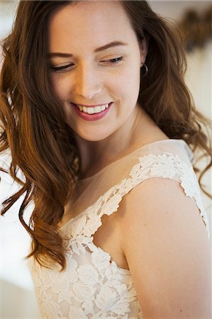 simsearch:6118-08971470,k - A young woman with long brown hair wearing a lace dress, looking over her shoulder. Photographie de stock - Premium Libres de Droits, Code: 6118-08971434