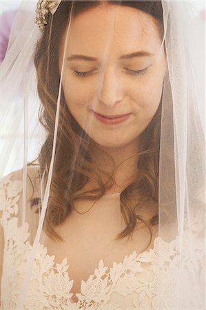 simsearch:6118-08971470,k - A young woman, a bride in a wedding dress with lace bodice, and a net veil over her face. Photographie de stock - Premium Libres de Droits, Code: 6118-08971439