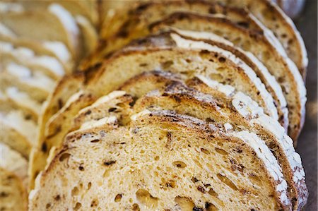 simsearch:6118-08971609,k - Close up of a freshly baked loaf of bread cut into slices. Foto de stock - Royalty Free Premium, Número: 6118-08971544