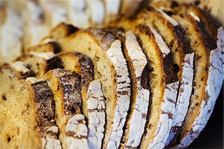 simsearch:6118-08971609,k - Close up of a freshly baked loaf of bread cut into slices. Foto de stock - Royalty Free Premium, Número: 6118-08971545