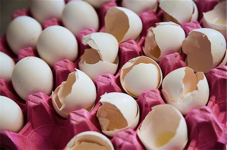 Close up high angle view of white eggs and cracked white egg shells in a pink cardboard tray. Photographie de stock - Premium Libres de Droits, Code: 6118-08971552
