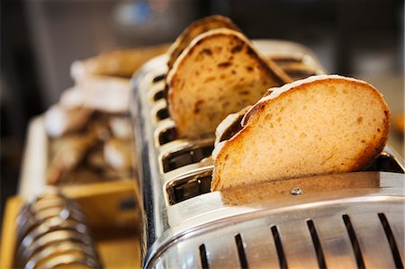 simsearch:6118-08971609,k - Close up of slices of bread in a stainless steel toaster. Foto de stock - Royalty Free Premium, Número: 6118-08971560