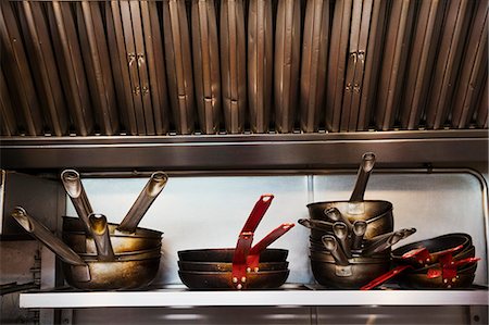 simsearch:6118-08971609,k - Close up of stacks of pots and pans on a shelf in a restaurant kitchen. Foto de stock - Royalty Free Premium, Número: 6118-08971586