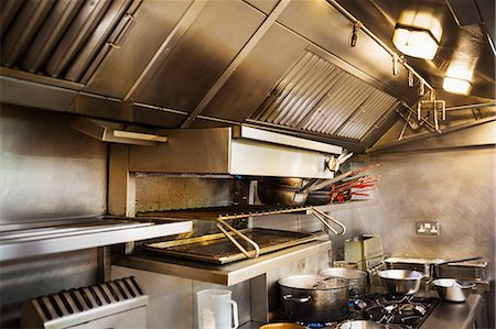 Interior view of restaurant kitchen, pots on stovetop, grill and extractor hood. Stock Photo - Premium Royalty-Free, Code: 6118-08971590
