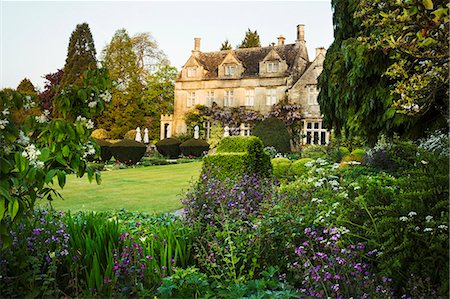 Exterior view of a 17th century country house from a garden with flower beds, shrubs and trees. Stock Photo - Premium Royalty-Free, Code: 6118-08971529