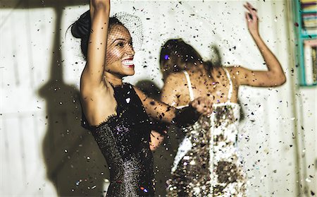 simsearch:6118-09039257,k - Two young women laughing and waving their arms and dancing at a glitter party. Stock Photo - Premium Royalty-Free, Code: 6118-08991348