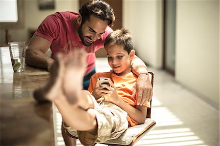 simsearch:6118-08991513,k - A man and a boy looking at a mobile phone screen. Foto de stock - Royalty Free Premium, Número: 6118-08991459