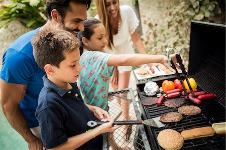 simsearch:6118-08991513,k - A family standing at a barbecue cooking food. Foto de stock - Royalty Free Premium, Número: 6118-08991510
