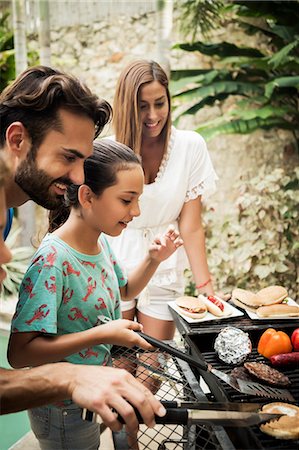 simsearch:6118-08991513,k - A family standing at a barbecue cooking food. Foto de stock - Royalty Free Premium, Número: 6118-08991511
