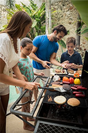 simsearch:6118-08991513,k - A family standing at a barbecue cooking food. Foto de stock - Royalty Free Premium, Número: 6118-08991514