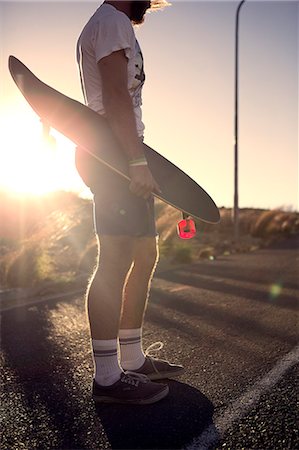 simsearch:6118-08991633,k - A young man standing on a road and holding a skateboard. Stock Photo - Premium Royalty-Free, Code: 6118-08991653