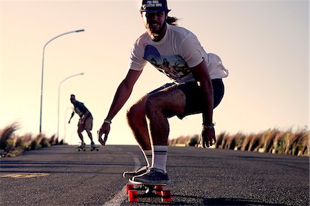 simsearch:6118-09039292,k - A young man skateboarding on a road. Foto de stock - Sin royalties Premium, Código: 6118-08991650