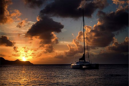 sailboat sunset - Sailing boat on the ocean under a cloudy sky at sunset. Stock Photo - Premium Royalty-Free, Code: 6118-08991663