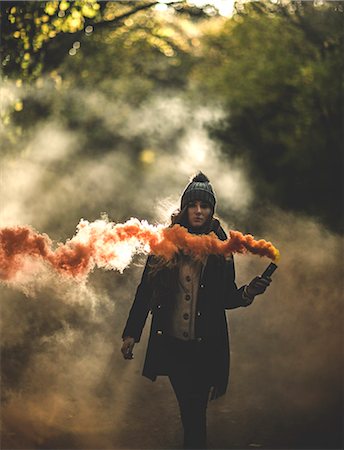 simsearch:6118-08991633,k - A young woman waving an orange smoke flare in a forest. Stock Photo - Premium Royalty-Free, Code: 6118-08991660