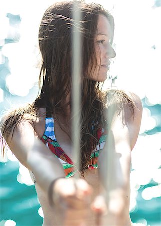 A young woman on board a yacht holding onto rope. Photographie de stock - Premium Libres de Droits, Code: 6118-08991674