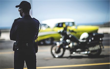 simsearch:6118-08991686,k - Rear view of man standing looking out at a parking lot. Motorbike and a classic car in the background. Photographie de stock - Premium Libres de Droits, Code: 6118-08991683