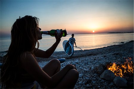 sunset drinking beer - A pair of young people gathered on a beach. Stock Photo - Premium Royalty-Free, Code: 6118-08991639