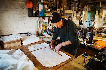 simsearch:6118-08660198,k - Man in a sailmaker's workshop measuring a piece of fabric for a sail. Photographie de stock - Premium Libres de Droits, Code: 6118-08928153