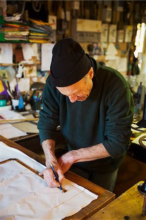 Man in a sailmaker's workshop measuring a piece of fabric for a sail. Stockbilder - Premium RF Lizenzfrei, Bildnummer: 6118-08928152