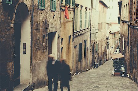 europe paving - A couple, man and woman walking up a steep cobbled  narrow street in Siena city. Stock Photo - Premium Royalty-Free, Code: 6118-08928336