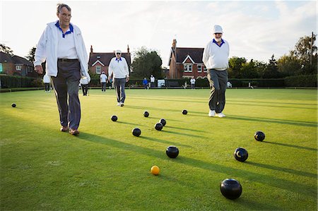simsearch:6118-07351858,k - Three lawn bowls players, men walking across the green, the playing surface, at an end with bowls clustered around the yellow jack ball. Stock Photo - Premium Royalty-Free, Code: 6118-09059649