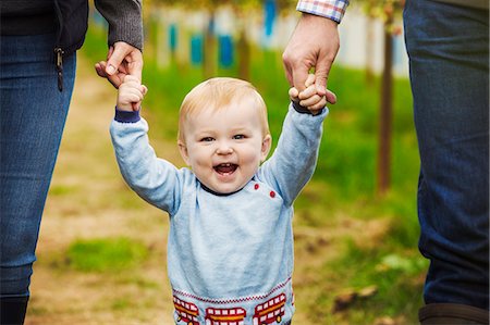 Two adults and a baby boy holding hands in a polytunnel at a fruit farm. Stock Photo - Premium Royalty-Free, Code: 6118-09059664