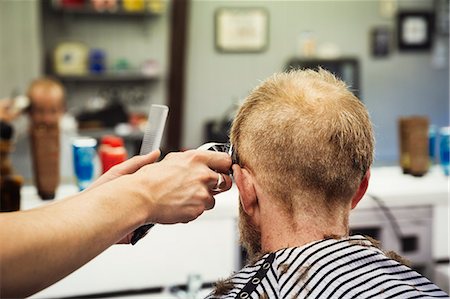 simsearch:400-08955424,k - A customer sitting in the barber's chair, and a barber using an electric shaver to shave his head. Stock Photo - Premium Royalty-Free, Code: 6118-09059690