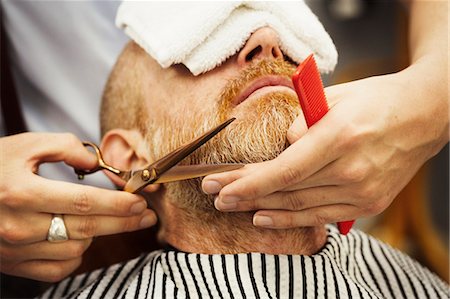 simsearch:400-08955424,k - A customer sitting in the barber's chair, with a hot towel on his face, and a barber trimming his beard. Stockbilder - Premium RF Lizenzfrei, Bildnummer: 6118-09059697