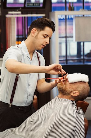 simsearch:400-08955424,k - A customer sitting in the barber's chair, with a hot towel on his face, and a barber trimming his beard. Stock Photo - Premium Royalty-Free, Code: 6118-09059696