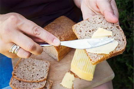 spreading butter on bread - A person buttering bread with a knife, food preparation. Stock Photo - Premium Royalty-Free, Code: 6118-09059760