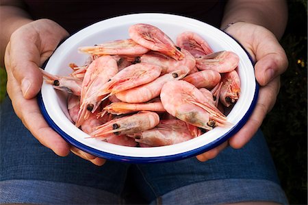 A person holding a bowl of fresh cooked prawns. Stock Photo - Premium Royalty-Free, Code: 6118-09059761