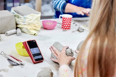 stanley knife - People seated at a workbench in a pottery studio. A woman using a sketch on her phone as reference to model clay. Stock Photo - Premium Royalty-Free, Code: 6118-09059830
