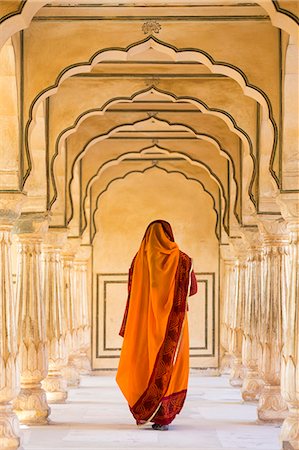 Rear view of woman wearing orange sari walking along a colonnade. Photographie de stock - Premium Libres de Droits, Code: 6118-09076676