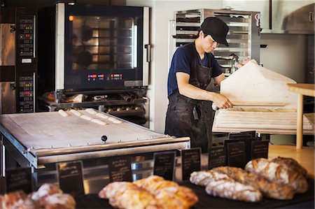 simsearch:6118-09079618,k - Man working in a bakery, preparing large tray with dough for rolls, oven in the background. Stock Photo - Premium Royalty-Free, Code: 6118-09079241