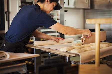 simsearch:6118-08660017,k - Man working in a bakery, cutting dough for rolls with large cutter. Stock Photo - Premium Royalty-Free, Code: 6118-09079242