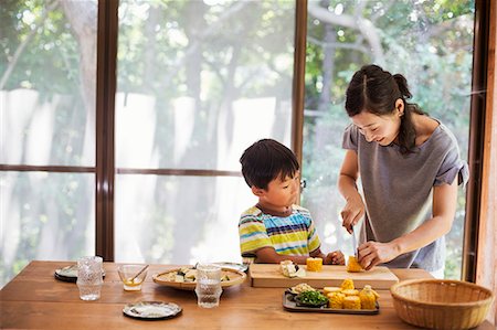 Woman and boy standing at a table, preparing corn on the cob, smiling. Foto de stock - Sin royalties Premium, Código: 6118-09079297