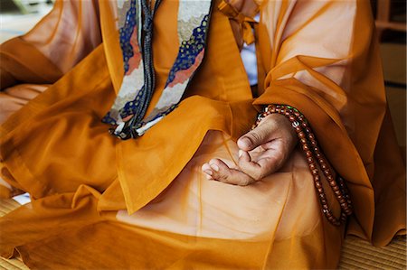 simsearch:878-07442720,k - Close up of Buddhist monk wearing golden robe sitting cross legged on the floor, meditating, Buddhist hand gesture. Stock Photo - Premium Royalty-Free, Code: 6118-09079377