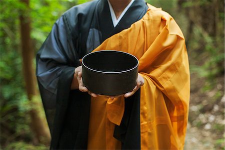 simsearch:6118-09079564,k - Close up of Buddhist monk wearing black and yellow robe, holding singing bowl. Fotografie stock - Premium Royalty-Free, Codice: 6118-09079389