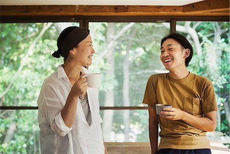 simsearch:6118-09079349,k - Man and woman standing indoors, holding coffee mugs, lookign at each other, smiling. Stock Photo - Premium Royalty-Free, Code: 6118-09079336