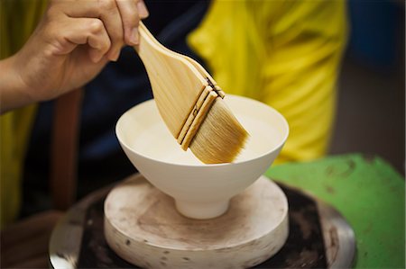 simsearch:6118-08761920,k - Close up of person working in a Japanese porcelain workshop, glazing white bowls with paintbrush. Stock Photo - Premium Royalty-Free, Code: 6118-09079443