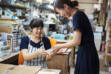 simsearch:6118-08762022,k - Two smiling women sitting and standing in a workshop, looking at Japanese porcelain bowl. Foto de stock - Sin royalties Premium, Código: 6118-09079460