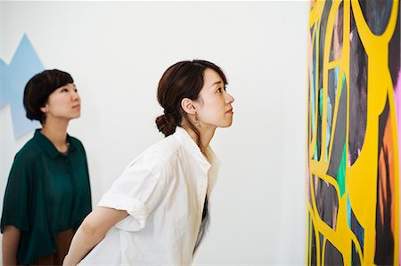 Two women standing in an art gallery, looking at an abstract modern painting. Stock Photo - Premium Royalty-Free, Code: 6118-09079470