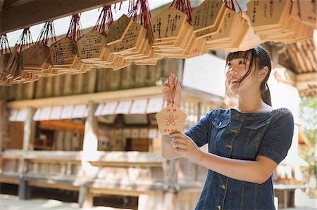 simsearch:6118-09079564,k - Young woman wearing blue dress looking at wooden fortune telling plaques at Shinto Sakurai Shrine, Fukuoka, Japan. Fotografie stock - Premium Royalty-Free, Codice: 6118-09079583