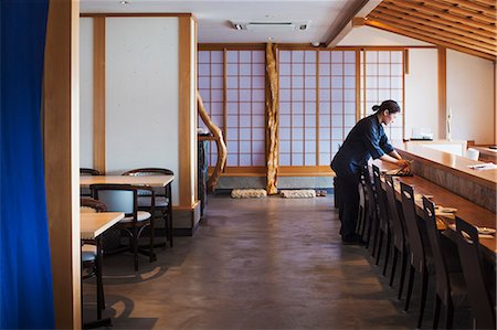 simsearch:6118-09079590,k - Waitress standing at a counter in a Japanese sushi restaurant, preparing place settings. Stock Photo - Premium Royalty-Free, Code: 6118-09079592