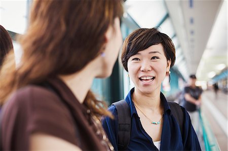 Two women standing indoors, looking at each other, smiling. Stock Photo - Premium Royalty-Free, Code: 6118-09079507