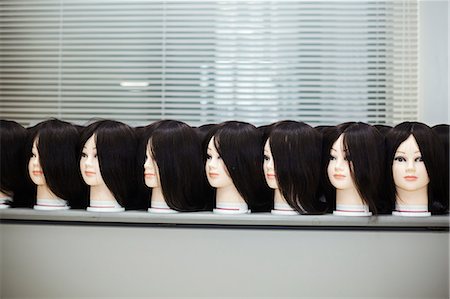 simsearch:6118-09079638,k - Large group of mannequin heads with brown wigs in a row on a table. Foto de stock - Royalty Free Premium, Número: 6118-09079638