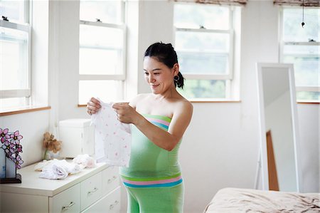 simsearch:693-03315753,k - A pregnant woman in a baby's nursery room, folding baby clothes. Stock Photo - Premium Royalty-Free, Code: 6118-09079785