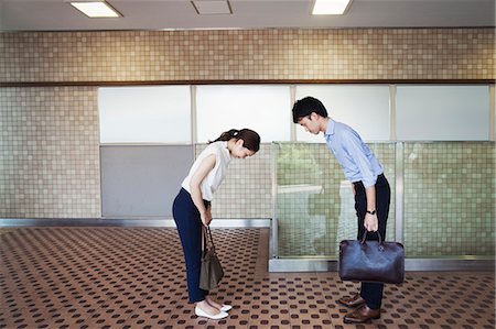 Two people greeting, a man and young woman bowing from the waist when they meet in a subway. Stock Photo - Premium Royalty-Free, Code: 6118-09079721