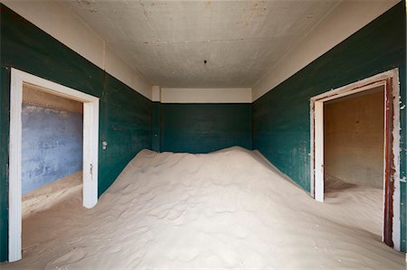 A deserted building, a room with painted walls and two doorways, and a heap of sand engulfing half the room. Stock Photo - Premium Royalty-Free, Code: 6118-09018155